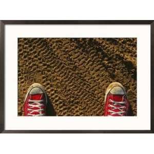  Red sneakers on soil patterned with tire tracks Framed Art 